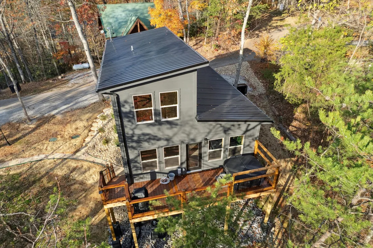 The cabin’s exterior, framed by a modern deck and surrounded by lush woodland, evokes a sense of tranquility and seclusion. The image hints at relaxing moments on the deck after action-packed days, with nature enveloping the space in calm.