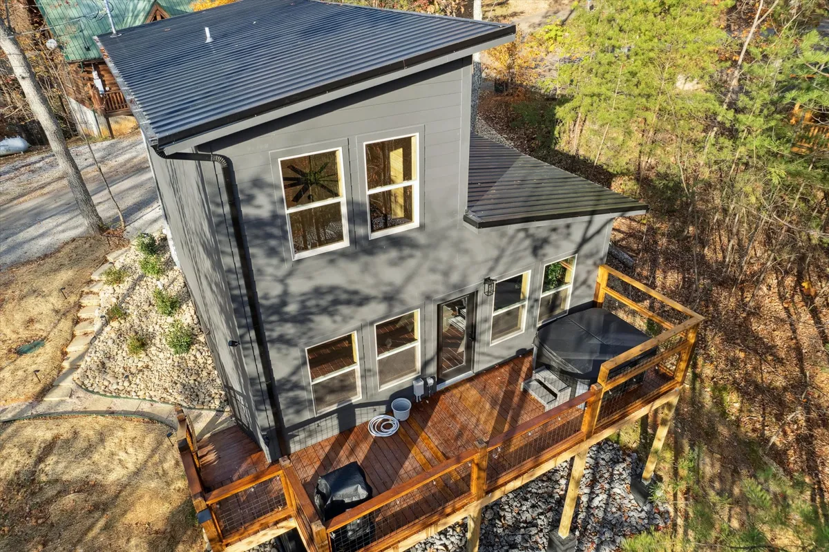 A contemporary exterior deck area overlooking a serene natural landscape. The deck is spacious enough for group socializing, with views of surrounding trees and open sky—ideal for stargazing, morning coffee, or sunset chats with friends.