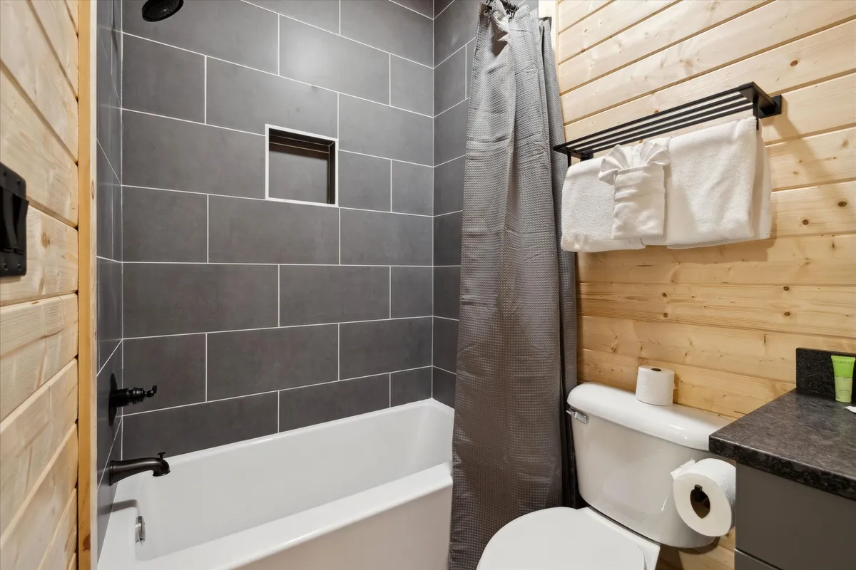 A calming bathroom with elegant wood paneling, a separate bathtub, a shower area, and a conveniently placed towel rack. The space is designed for both relaxation and rejuvenation, ideal for a soothing bath or a refreshing shower.